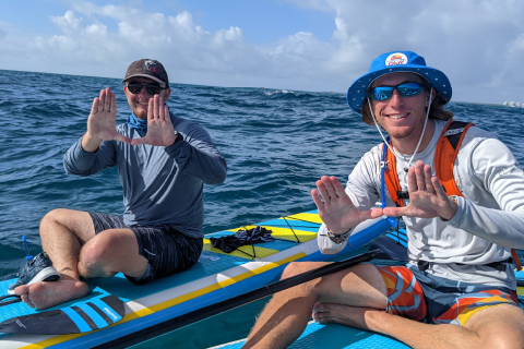 Two students throwing up the U on paddleboard